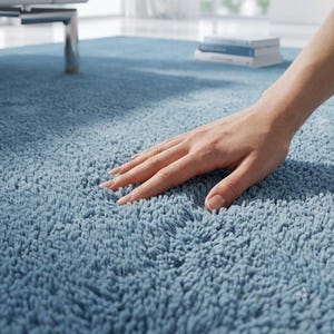 Op de afbeelding: Een pluche, lichtblauw vloerkleed met een dikke, hoogpolige textuur. Het oppervlak van het kleed bestaat uit dichte, zachte vezels die een diep, getextureerd uiterlijk cre&euml;ren, wat zorgt voor een consistente effen kleur over het hele oppervlak.