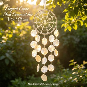 May include: A circular dreamcatcher wind chime featuring a white webbed frame adorned with translucent, iridescent capiz shell discs hanging from thin strings. The text Elegant Capiz Shell Dreamcatcher Wind Chime and Handmade Boho Home Decor is visible.
