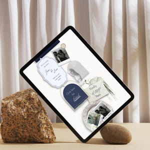 May include: A digital tablet displaying a wedding invitation template with a white background, featuring a navy blue arch button labelled Click here for Details, a cream envelope labelled Kindly RSVP Here, and various black and white photos.