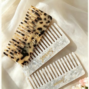 Puede incluir: Tres peines rectangulares de dientes anchos. Un peine presenta un patrón de carey marrón y negro con el nombre Maria grabado en oro. Dos peines tienen un acabado nacarado blanco con los nombres Sarah y Jessica escritos en color oro.
