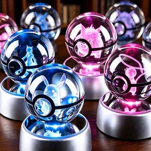 Puede incluir: Una colección de adornos esféricos de cristal con figuras grabadas con láser en su interior, cada uno sobre una base circular plateada. Las esferas están iluminadas con luces LED azules y rosas, mostrando varias siluetas de criaturas.