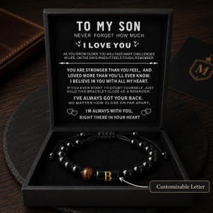 May include: A black beaded bracelet with a single brown tiger eye bead and a central black cylindrical bead featuring the gold letter B. The bracelet is presented in a black gift box with a printed message addressed to a son, including the text I LOVE YOU.