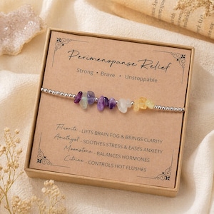 May include: A silver beaded bracelet with colorful gemstone beads, presented in a brown box. The box reads "Perimenopause Relief" with stone benefits listed below. The bracelet features purple, yellow, and white stones.