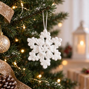 May include: A white crocheted snowflake ornament with a six-pointed star design, featuring intricate yarn loops and a central cluster. The ornament is suspended by a thin white string, showcasing a textured, handmade appearance with a clean finish.