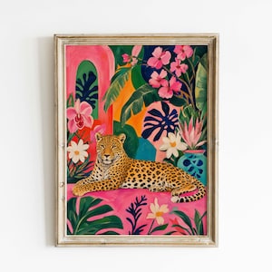 May include: A framed art print featuring a leopard resting in a vibrant tropical setting. The artwork showcases a leopard with a spotted coat, surrounded by pink, green, and orange foliage and flowers. The frame is a light, neutral color.