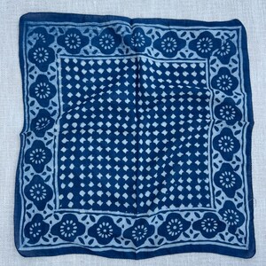 May include: A square bandana featuring a deep blue and light blue color scheme. The central area displays a repeating grid of small diamond shapes, while the border is decorated with a continuous pattern of stylized floral motifs.