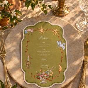 May include: A die-cut olive green menu card with a scalloped edge, featuring illustrations of suns, a winged horse, a crescent moon, a candle holder, and a floral arrangement. The text reads Menu, Entree, Main, Dessert, and Rose & David 25/06/2026.