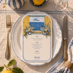 May include: A rectangular menu card with rounded corners featuring a painted illustration of a blue sea view through a window with yellow shutters and floral arrangements. The text includes Menu, Entree, Main, Dessert, and the names Olivia + Daniel 25/06/2030.