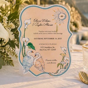 May include: A die-cut wedding invitation card with a scalloped edge, featuring a peach-colored background, illustrations of two swans and calla lilies, and a celestial sun motif. The text reads: Olivia Wilson & Taylor Alonso, Saturday, September 14, 2025.