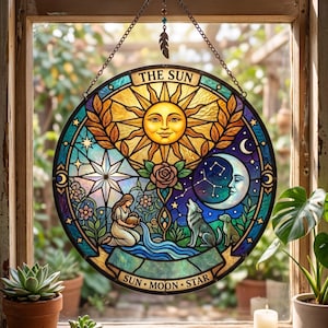 May include: A circular stained glass suncatcher featuring a central sun face with the text THE SUN at the top. The design includes a person pouring water, a wolf, a crescent moon, a star, and a rose. The bottom banner reads SUN MOON STAR.