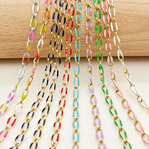 Puede incluir: Una colección de nueve cadenas de metal con eslabones ovalados y detalles en esmalte de colores. Las cadenas incluyen una opción en tono plateado y ocho en tono dorado, cada una decorada con colores vibrantes de esmalte que incluyen naranja, azul, negro, rojo, turquesa, morado, verde, rosa y blanco.