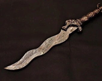 May include: A wavy-bladed dagger featuring a distinct Damascus steel pattern with swirling gray and silver lines. The handle is crafted from dark metal, showcasing intricate relief carvings of a lion head at the guard and a textured grip.