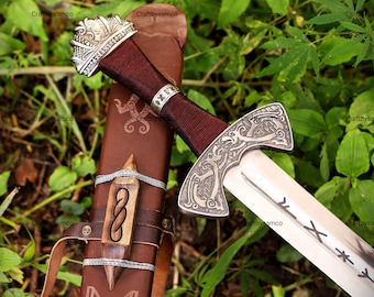May include: A sword with a silver-toned pommel and crossguard featuring intricate knotwork designs, a dark maroon wrapped grip, and a steel blade engraved with runic symbols. The sword is paired with a brown leather scabbard with wood accents.