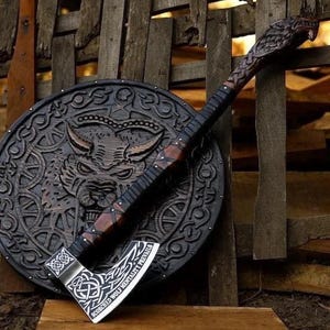May include: A dark brown wooden axe with a carved wolf head on the handle and a silver blade featuring intricate knotwork patterns and the text "SCORCHED WOLF MENTALITY PREVAILS," resting against a circular black shield with a wolf face carving.