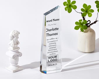 May include: A clear, wedge-shaped glass award trophy featuring the printed text "Award Name," "Charlotte Thomas," "In recognition of outstanding achievement, unmatched determination, and extraordinary excellence," "YOUR LOGO," and "2026.08.23."