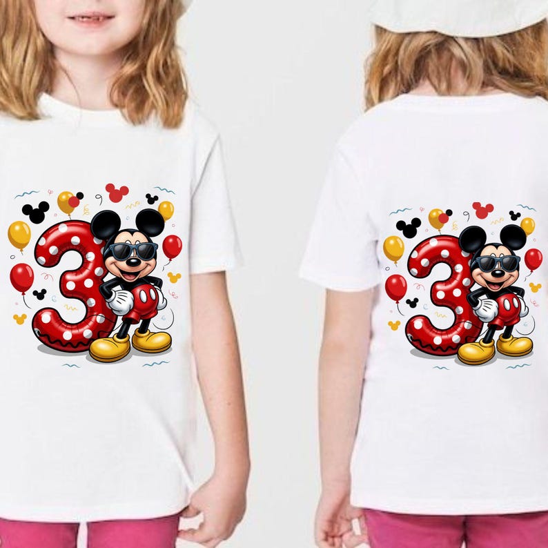 May include: A white t-shirt featuring a graphic of a cartoon mouse wearing sunglasses, standing next to a large red number three with white polka dots. The design includes red and yellow balloons, small confetti, and mouse ear silhouettes.
