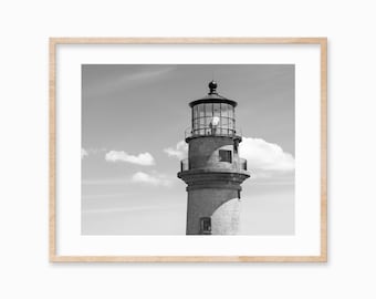 May include: A black and white photograph of a lighthouse against a cloudy sky. The lighthouse is made of stone and has a white, glass lantern on top.