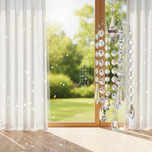 Puede incluir: Un atrapasoles de cristal colgante que presenta m&uacute;ltiples hilos de cuentas de vidrio transparente facetado y prismas en forma de l&aacute;grima suspendidos de un marco de metal plateado, dise&ntilde;ado para refractar la luz y crear reflejos de arco&iacute;ris.