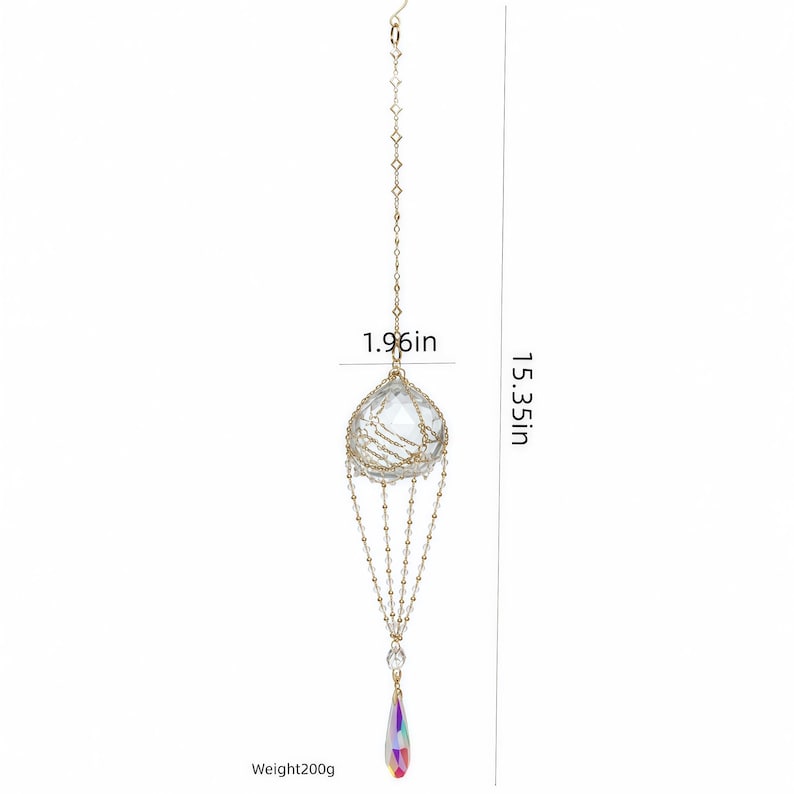 Puede incluir: Un adorno de cristal colgante con una esfera transparente facetada en una jaula de alambre dorado, suspendido por una cadena fina. Mide 4,98 cm de ancho y 39 cm de largo, con un colgante iridiscente en forma de l&aacute;grima y un peso de 200g.