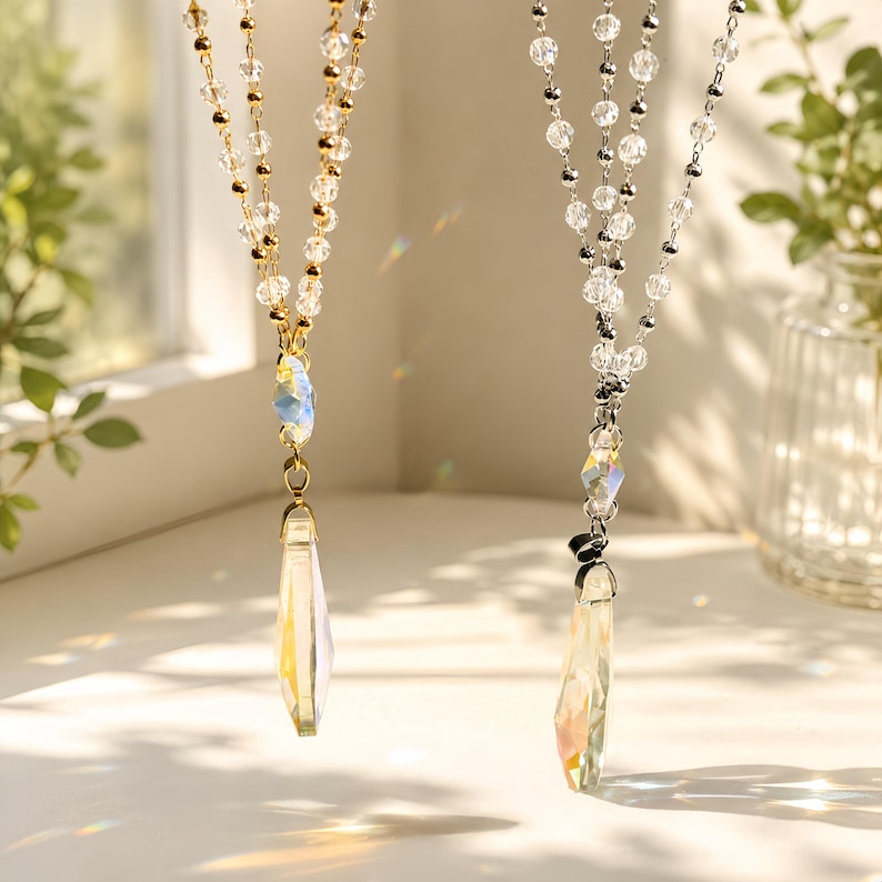 Puede incluir: Dos collares con cuentas facetadas transparentes y cadenas met&aacute;licas. Uno tiene una cadena dorada y el otro una cadena plateada. Cada collar incluye una cuenta central facetada y un largo colgante iridiscente en forma de l&aacute;grima.