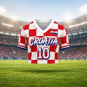 May include: A red and white checkered Croatia soccer jersey with the word "CROATIA" in white script and the number "10" in blue. The jersey has a V-neck and a small Croatian flag on the upper right. The sleeves have blue trim.