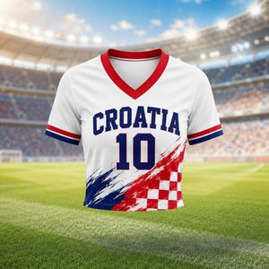 Pode incluir: Camisola de futebol branca da Cro&aacute;cia com detalhes em vermelho e azul. A camisola apresenta a palavra "CROATIA" em azul, o n&uacute;mero "10" e um design com as cores da bandeira croata. Tem decote em V e mangas curtas.