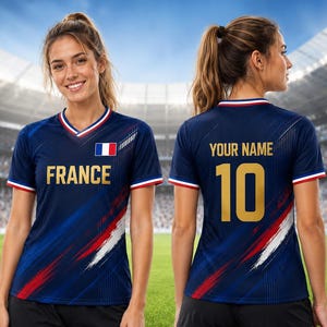 Puede incluir: Una camiseta de f&uacute;tbol azul marino de Francia con la palabra "FRANCE" en letras doradas. La camiseta tiene cuello en V con ribetes rojos y blancos, y la bandera francesa est&aacute; en el pecho. La parte trasera de la camiseta tiene el n&uacute;mero 10 en dorado.