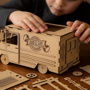 May include: A wooden toy food truck with the text "DAD'S CAR" is being assembled. The truck is made of light brown wood and has intricate details, including wheels, doors, and windows. Several unassembled pieces are scattered around the truck.