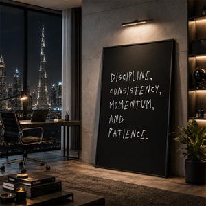Puede incluir: Una gran pieza de arte mural rectangular de color negro con texto blanco escrito a mano que dice: DISCIPLINE, CONSISTENCY, MOMENTUM, AND PATIENCE. La obra está enmarcada con un borde negro fino e iluminada por una pequeña luz de pared horizontal.