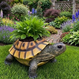 May include: A resin turtle planter with a yellow and brown shell, and a green plant growing from the top. The turtle is placed on green grass, with a garden in the background. The planter is a decorative garden ornament.