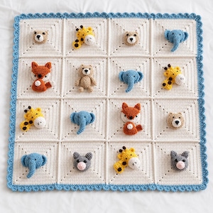 Può includere: Una coperta per neonati quadrata all'uncinetto con un motivo a griglia color crema e un bordo smerlato azzurro. Ogni quadrato contiene un'applicazione tridimensionale di animale imbottito, tra cui giraffe, elefanti, volpi e orsi.