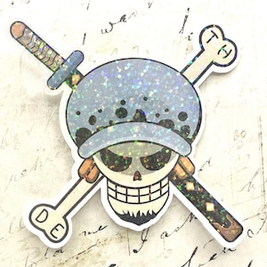 Könnte beinhalten: Ein holografischer Aufkleber mit einem Totenkopf, der einen gepunkteten Hut trägt und vor gekreuzten Knochen und einem Schwert platziert ist. Der Totenkopf hat einen dunklen Ziegenbart und die Knochen sind mit den Buchstaben D, E, T und H markiert.