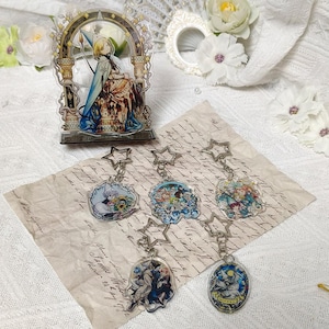 May include: An acrylic standee featuring a blonde character in a blue cloak within an ornate archway, accompanied by five acrylic keychains with star-shaped clasps, each displaying colorful anime-style illustrations of various characters.