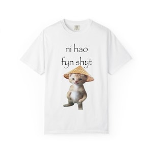 Könnte beinhalten: Weißes T-Shirt mit dem Text "ní hao fyn shyt" in Schwarz. Das Shirt zeigt ein Cartoon-Bild einer Katze mit Strohhut. Die Katze steht mit ihren Pfoten vor sich.