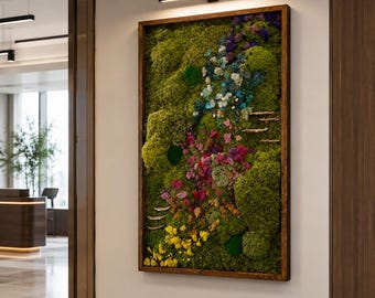 May include: A rectangular wall art piece featuring a dense arrangement of preserved green moss, accented with clusters of blue, purple, pink, and yellow dried flowers and small shelf fungi, all enclosed within a dark brown wooden frame.