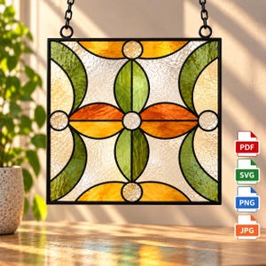May include: A square stained glass panel featuring a geometric floral pattern with orange, yellow, and green glass segments set in a black metal frame. The design includes clear textured glass sections and four small circular clear glass accents.