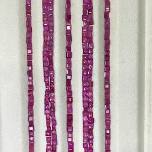 May include: Five vertical rows of small, square-cut, vibrant magenta-pink gemstones arranged in a parallel formation. Each individual stone features faceted surfaces that reflect light, creating a uniform and consistent appearance across all rows.
