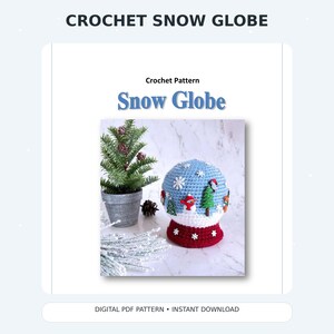 Może przedstawiać: Wzór szydełkowy zatytułowany CROCHET SNOW GLOBE i Snow Globe przedstawiający niebiesko-białą szydełkowaną kulę śnieżną z aplikacjami bałwana, drzew i płatków śniegu, obok małej sztucznej choinki w szarej doniczce.