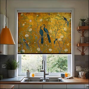 May include: A decorative window shade featuring a golden background with a detailed illustration of birds perched on flowering branches. The birds are primarily blue and teal, with white flowers and butterflies scattered throughout the design. The shade is installed in a kitchen setting.