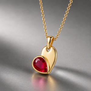 Könnte beinhalten: Eine Goldkette mit einem herzförmigen Anhänger. Der Anhänger besteht aus einem glatten, polierten Goldherz und einem kleineren, tropfenförmigen roten Edelstein in einer Goldfassung. Der Anhänger hängt an einer zierlichen Goldkette.