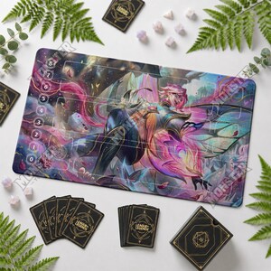May include: A rectangular League of Legends playmat featuring a vibrant, multi-colored illustration of a character with wings, surrounded by game board markings, numbers zero through eight, and a deck of black cards with gold geometric designs.