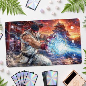 May include: A rectangular playmat featuring a character in a white martial arts uniform with a red headband, performing a blue energy blast. The mat includes printed game zones labeled Battlefield, Library, Graveyard, Lands, Exile, and Life Total.