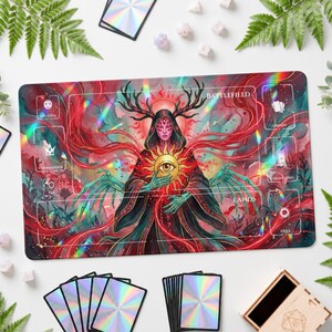 Könnte beinhalten: Eine rechteckige Spielmatte mit einer zentralen Figur mit Geweih und mehreren Augen, die ein leuchtendes goldenes Augensymbol hält. Das Design umfasst rote und türkisfarbene Farbverläufe, holografische Lichteffekte sowie beschriftete Zonen für Battlefield, Library, Graveyard, Lands und Exile.