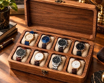 May include: A rectangular wooden watch box with a hinged lid and a metal latch, featuring eight individual compartments. Each compartment contains a beige fabric cushion holding a wristwatch with various dial colours, strap materials, and metal finishes.