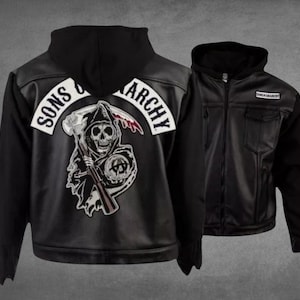 Może przedstawiać: Czarna kurtka z kapturem z dużą grafiką na plecach przedstawiającą ponurego żniwiarza trzymającego kosę i globus z napisem Sons of Anarchy. Z przodu kurtki znajduje się mała prostokątna naszywka z napisem Sons of Anarchy.