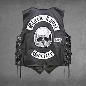 Può includere: Un gilet in pelle nera con allacciatura laterale tramite cordini neri e occhielli metallici. Il retro presenta una grande toppa bianca con un teschio, la scritta Black Label Society in carattere gotico e una piccola toppa con la scritta SDMF.