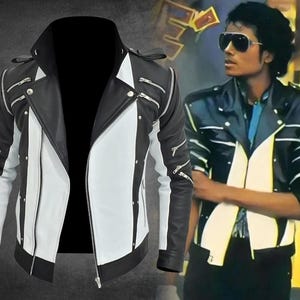 May include: A black and white jacket featuring multiple silver-toned zippers across the chest and sleeves, a wide lapel collar, and vertical color-blocked panels. The design includes metallic stud accents along the front closure and shoulder epaulets.