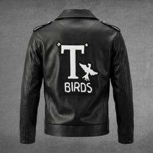 Peut inclure: Une veste en cuir noir avec un grand écusson blanc au dos. L'écusson présente une lettre T stylisée, une silhouette d'oiseau et le texte BIRDS en lettres blanches. La veste possède un col classique, des épaulettes et des manches longues.