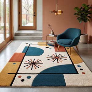 Op de afbeelding: Een rechthoekig vloerkleed met een crèmekleurige basis en een geometrisch patroon van blauwgroene, mosterdgele en roestoranje vormen. Het ontwerp bevat zwarte lijnen, cirkelvormige stippen en stervormige motieven in een gestructureerde compositie.