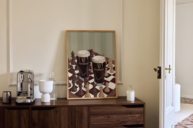 Peut inclure: Une impression d'art rectangulaire encadr&eacute;e repr&eacute;sentant un &eacute;chiquier avec des pi&egrave;ces en bois sombres et claires. Deux pintes de bi&egrave;re brune avec une mousse blanche cr&eacute;meuse, portant le logo Guinness, sont pos&eacute;es sur l'&eacute;chiquier.